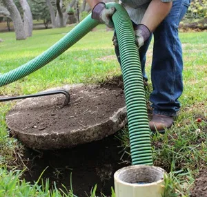 A technician pumping out a septic tank with a green hose